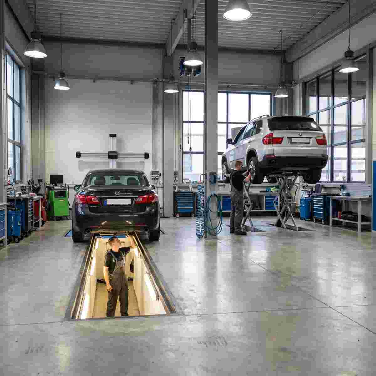 Moderne Autowerkstatt mit zwei Bereichen: Auto über Grube und Auto auf Hebebühne, freier Zugang.