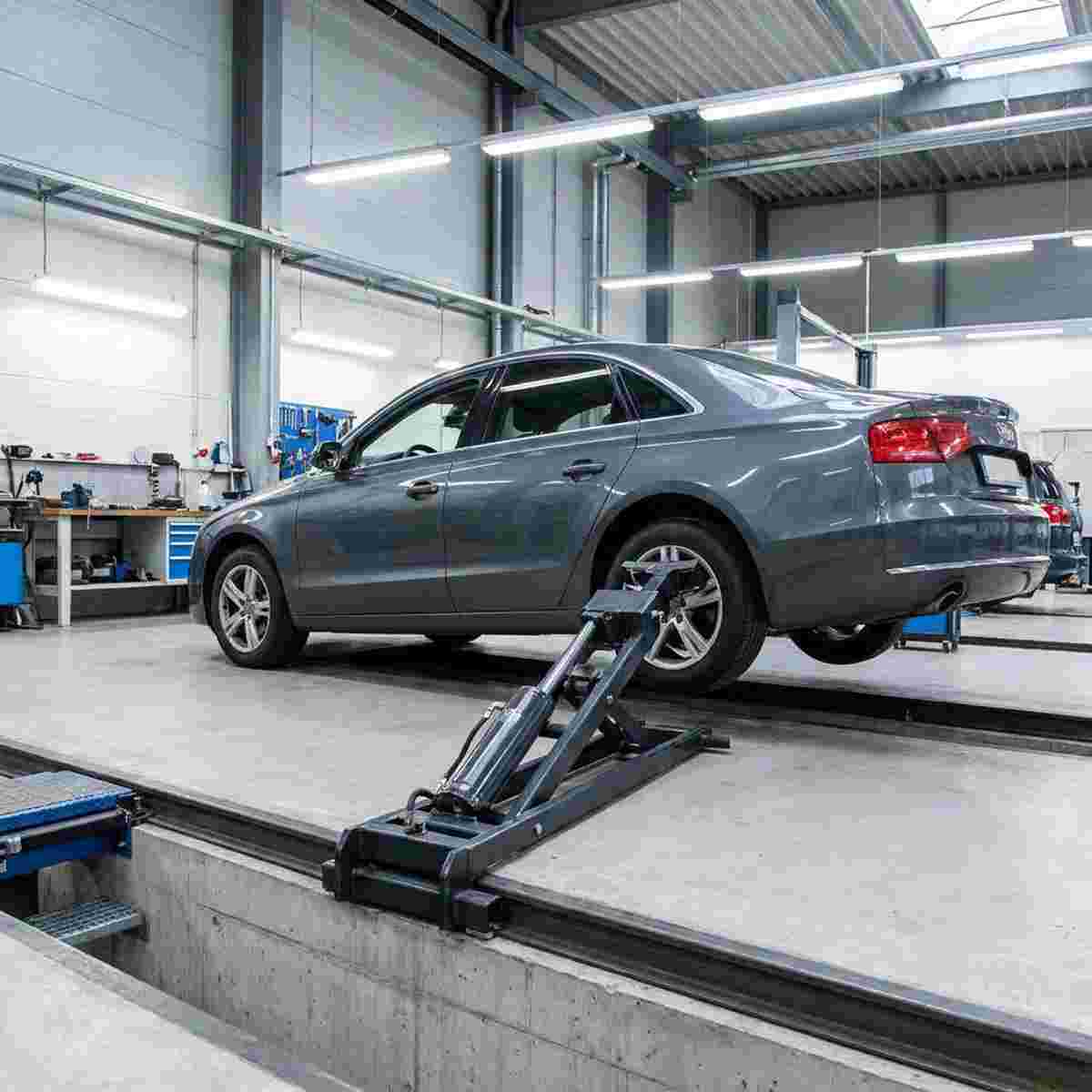 Moderne Autowerkstatt mit Auto über Graben, Achslift hebt nur die Achse.