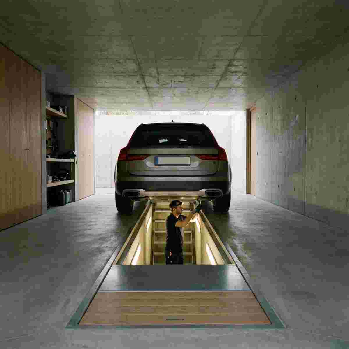 Moderne Garage: Auto über Inspektionsgrube, Techniker arbeitet am Unterboden; Grube verschließbar.