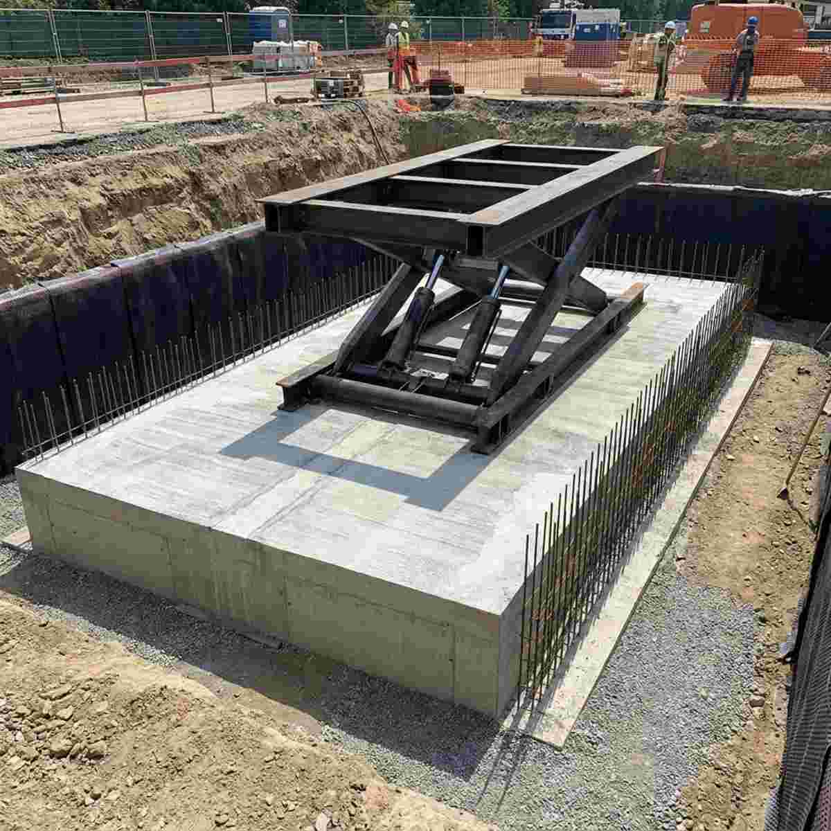 Baugrube mit schwerem Hydrauliklift auf Fundamentplatte, Bewehrung sichtbar, wasserdicht.